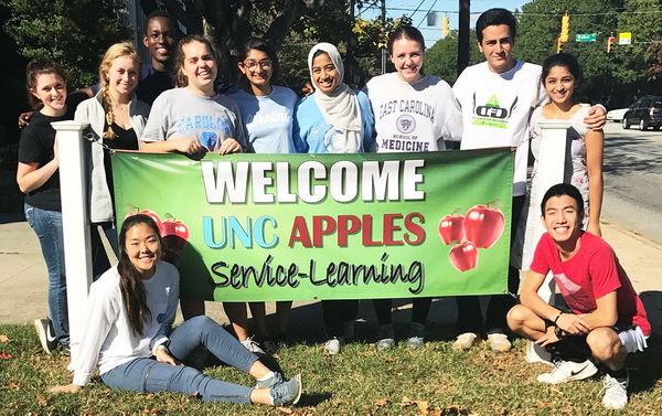 students stand with a banner that reads welcome UNC APPLES service-learning