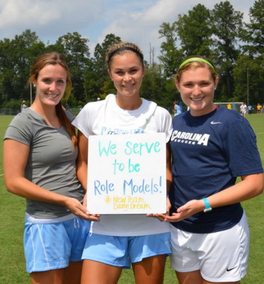 Womens soccer players holding why I serve sign