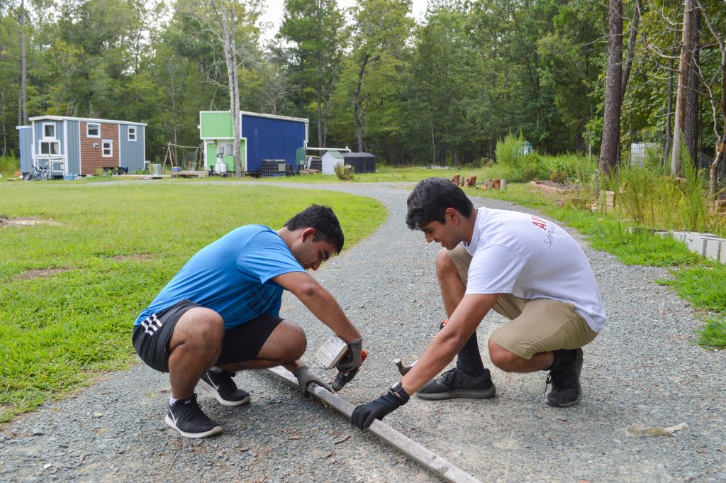 Kirti Patel and Sahil Sethi pull screws out of scrap wood at Wildwood Farm as part of SLI: Launch 2020.
