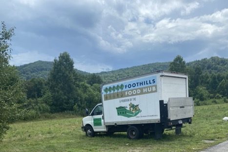 A Foothills Food Hub truck parked in the grass, with Appalachian mountains in the background.
