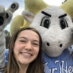 Hoffman poses with the UNC mascot Ramses. Ramses is holding one finger up to represent number one.