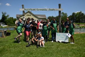 A group poses in front of a sign that says Peacehaven Community Farm
