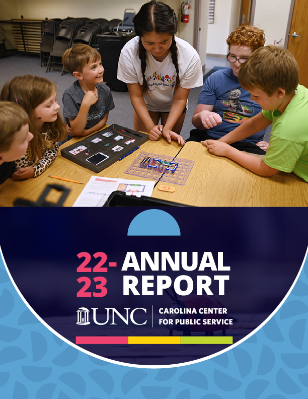 Front cover of the annual report. A woman with braided hair and a white t shirt demonstrates circuitry to a group of students looking on. Underneath the image is the text twenty two to twenty three annual report.